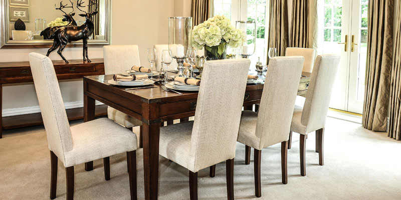 White upholstered dining chairs around a dark wood table
