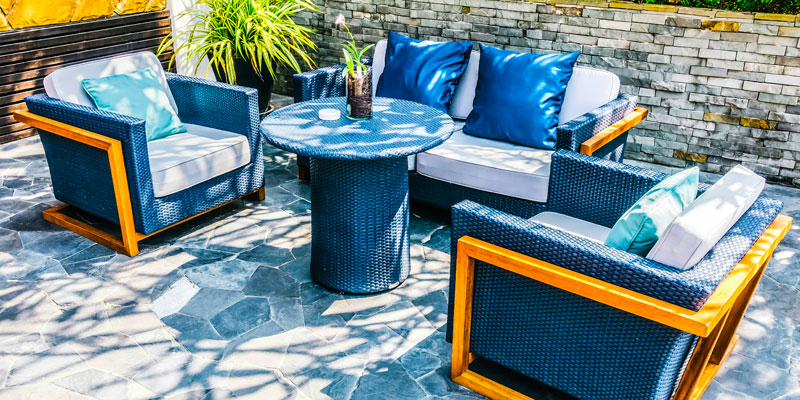 Blue patio armchairs and a table on a sunny stone terrace